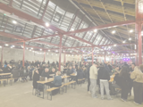 outdoor covered space with lots of people standing and sitting at benches